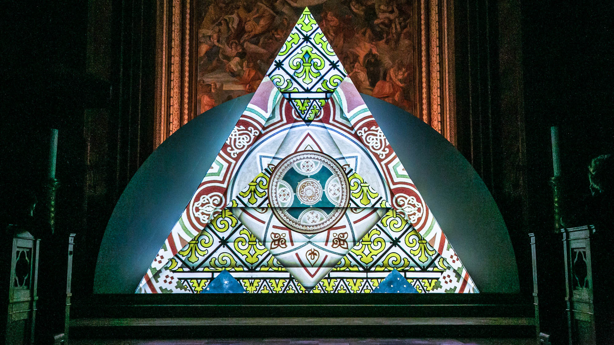 Image of a video art installation. Triangle with geometric and ornamental design. Light art show in a church