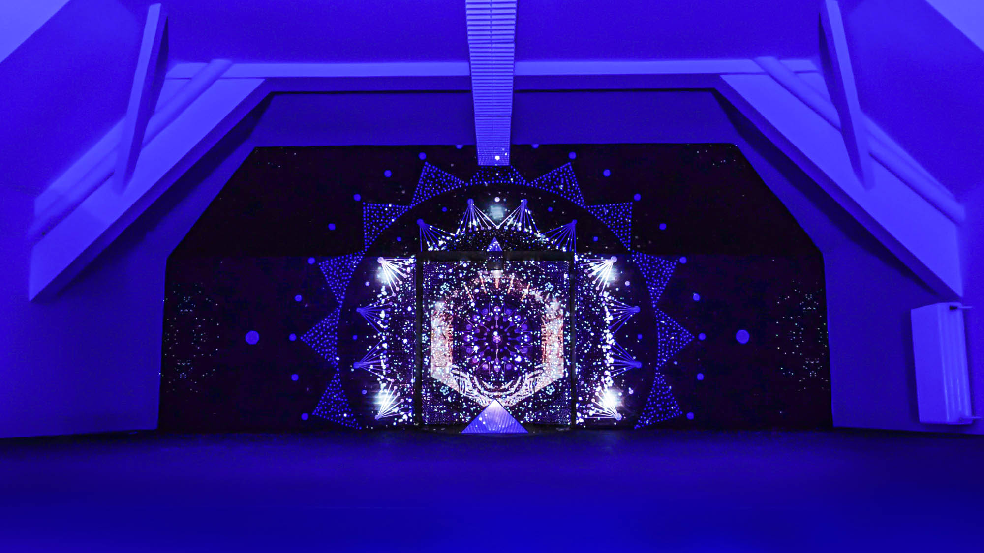 Image of a video art installation combined with a mural painting. Mandala geometric design with projection mapping art.