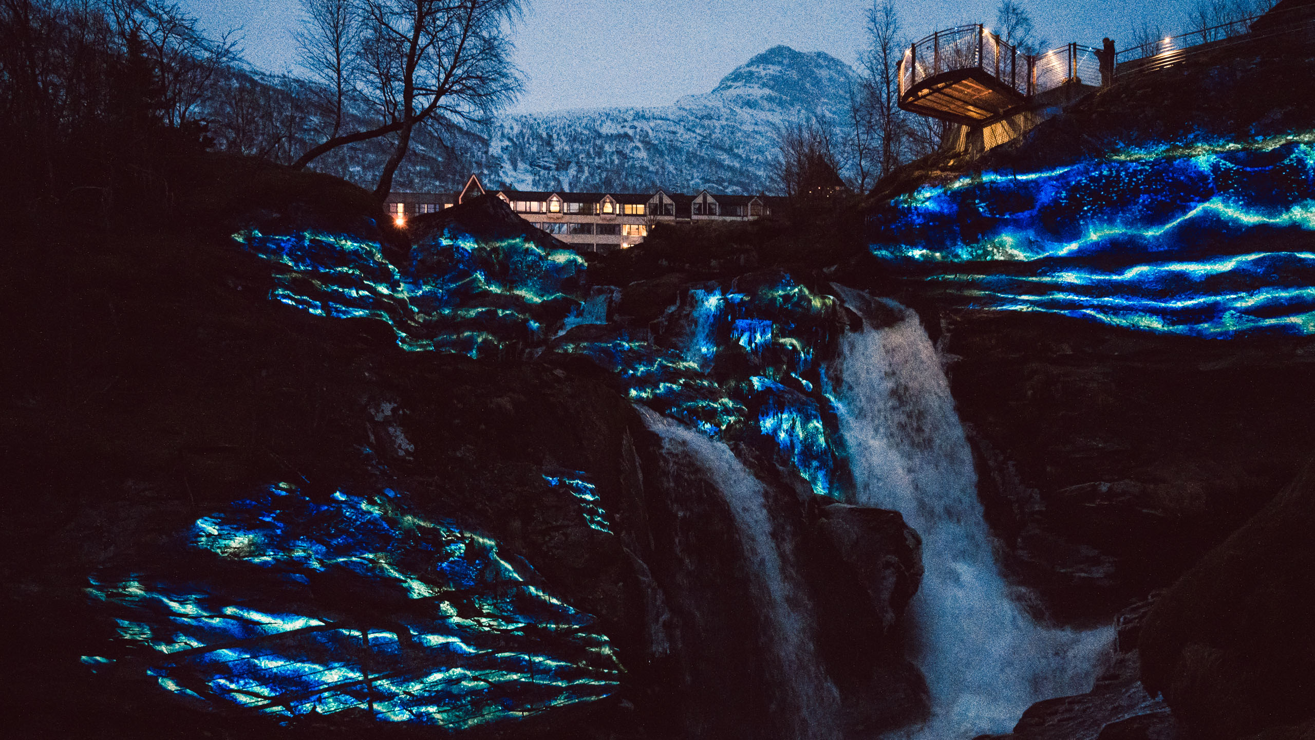 Rocks and waterfall with a blue projection mapping at geiranger fjord light festival