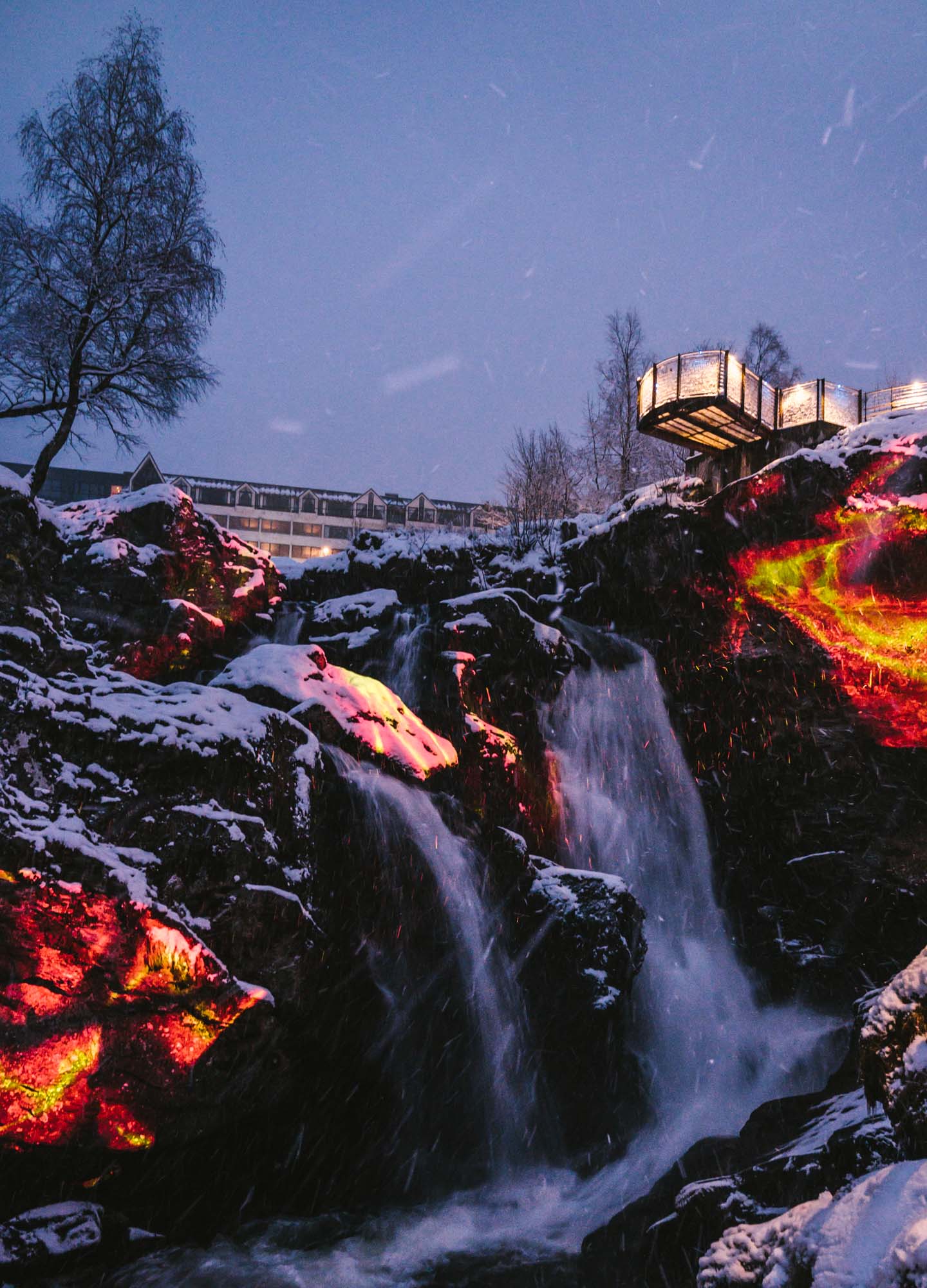 Video art projection with fire visuals on a waterfall and rocks