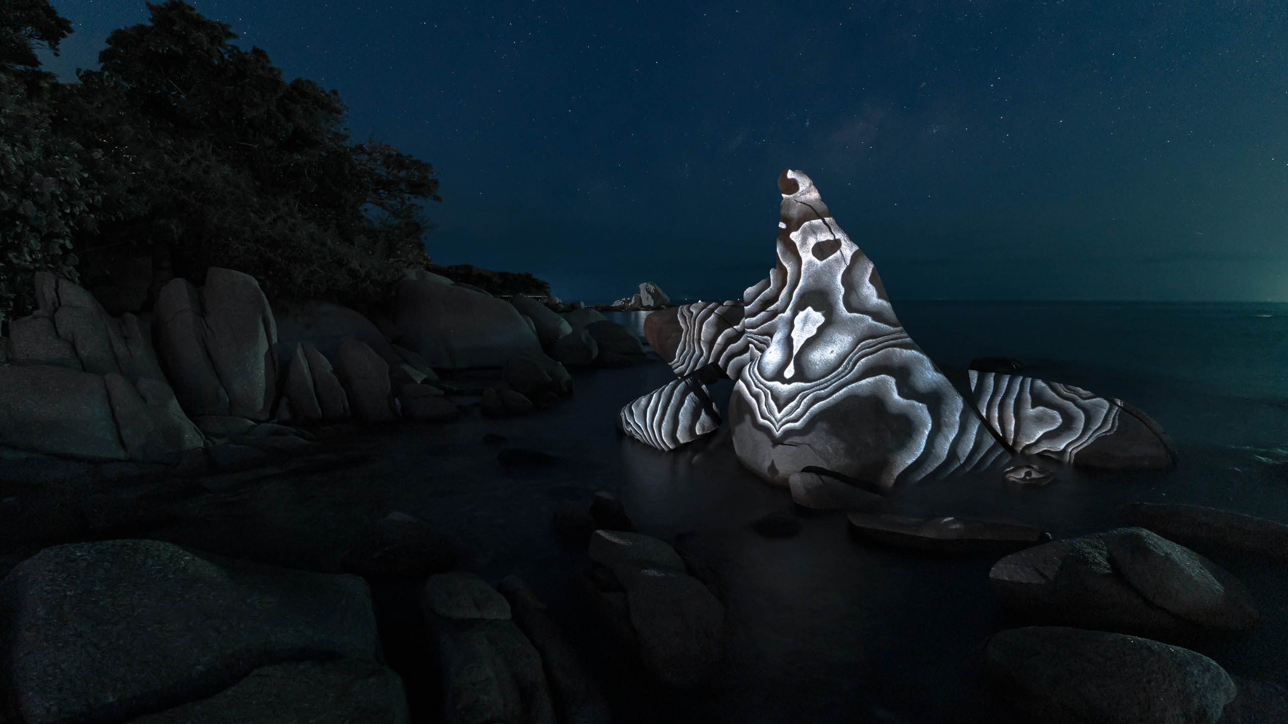 Landscape light artwork showing a beautiful rock with white geometric graphic pattern video projected onto it