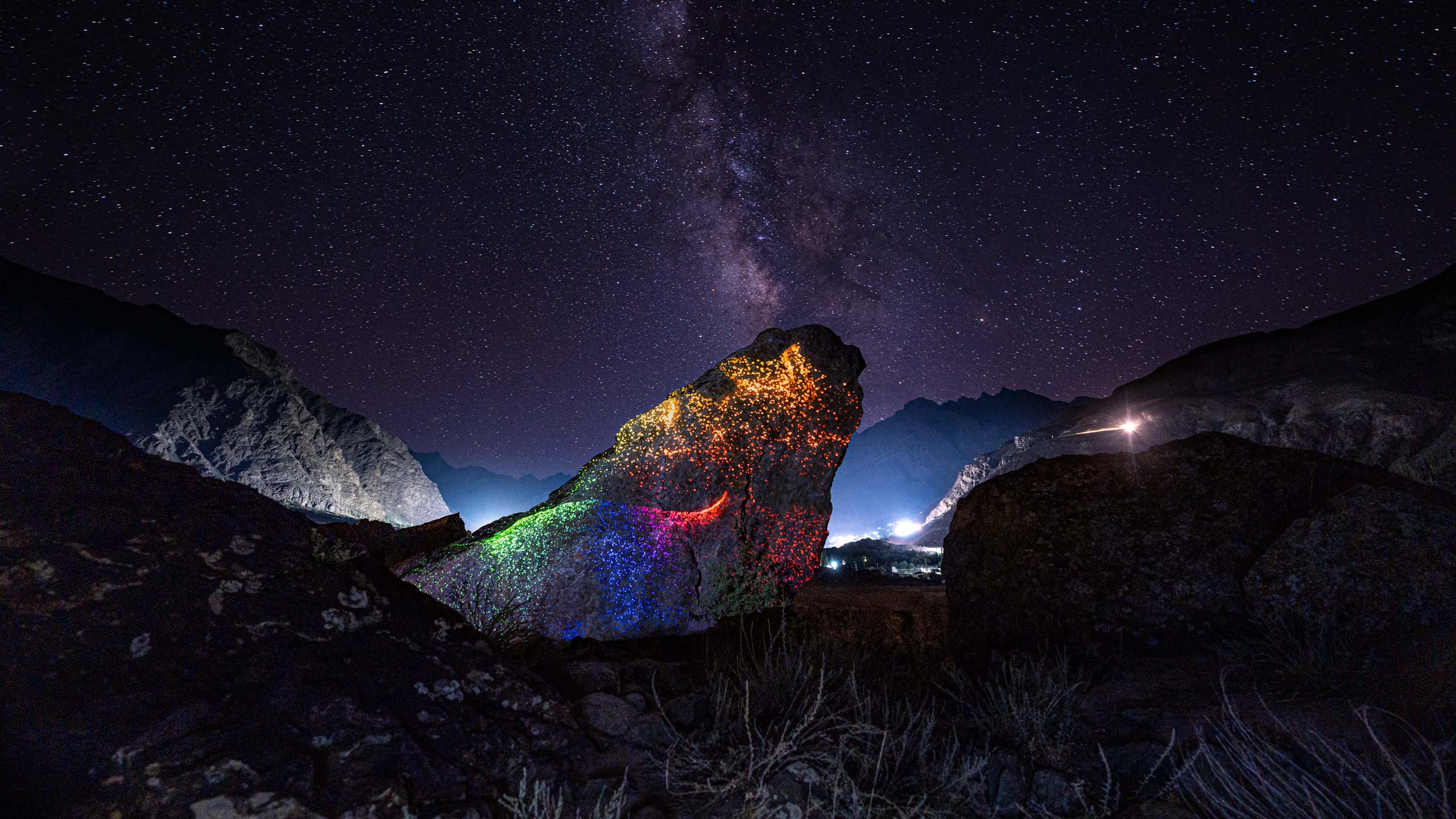 Colorful land-art installation at night on a boulder with milky way in the night sky in Ladakh, Himalaya