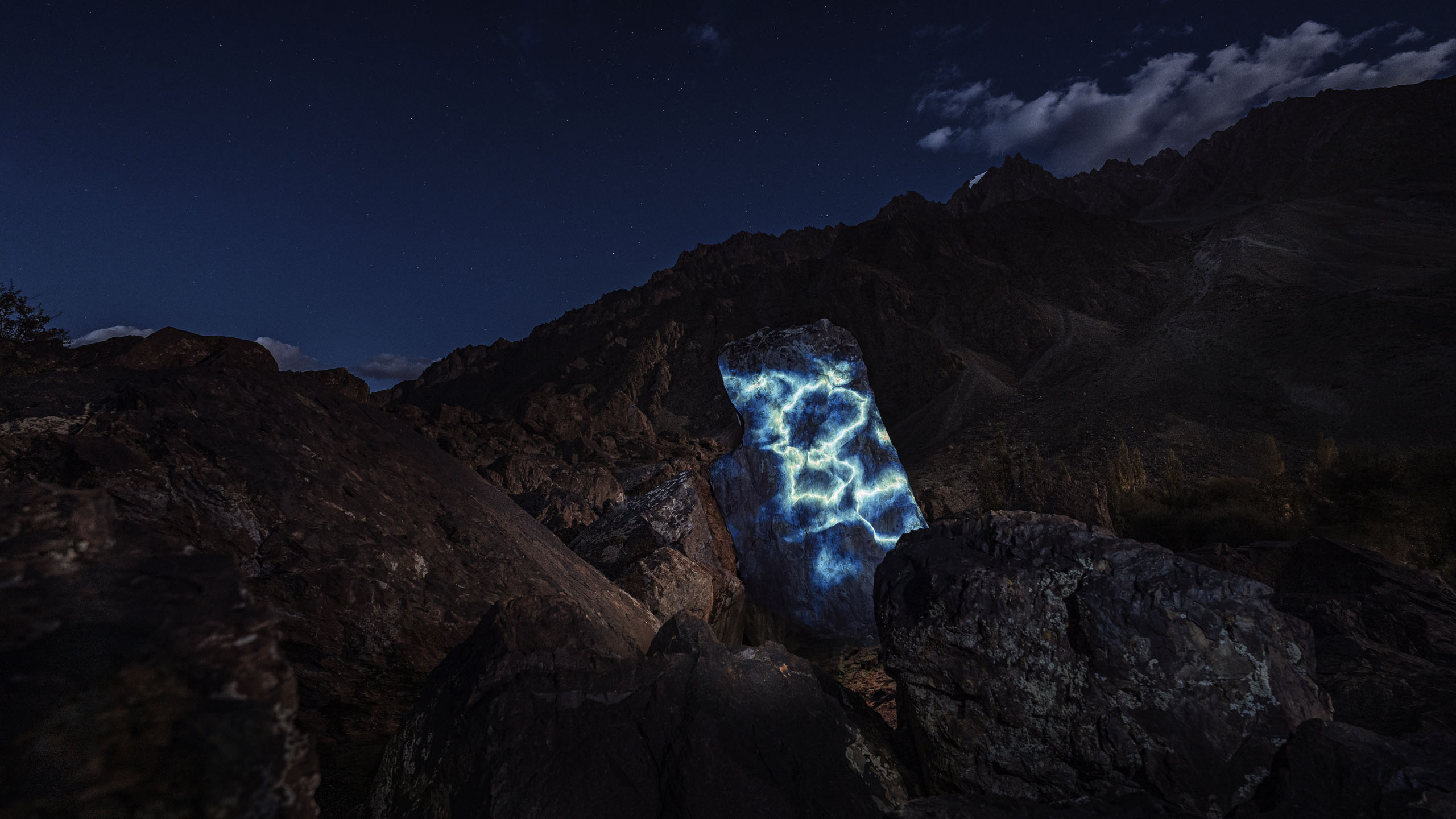 Land art projection mapping with blue abstract visuals on a rock in the Himalayan landscape 