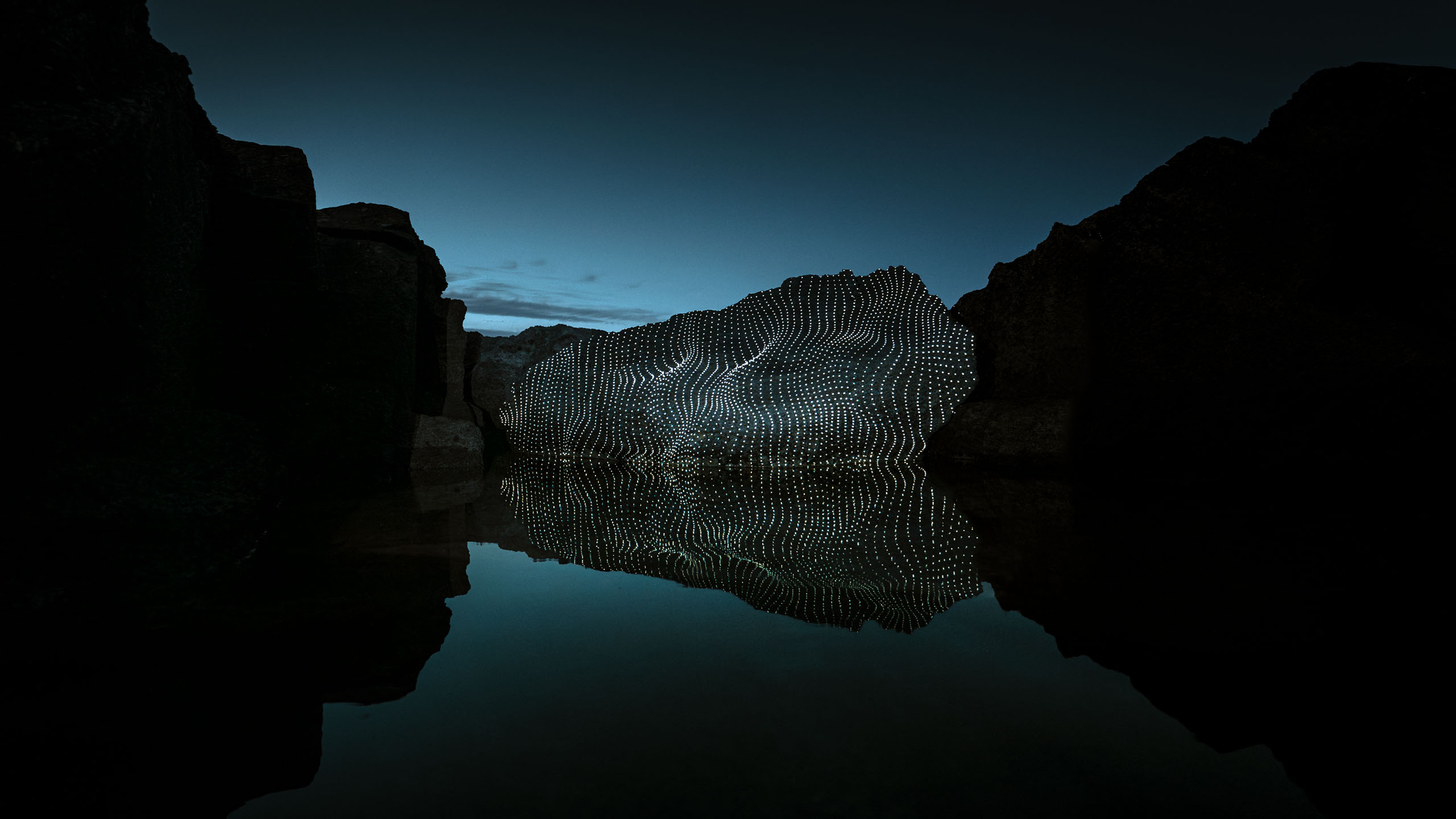 Video-mapping projections in nature on a beautiful boulder mirrored in calm water