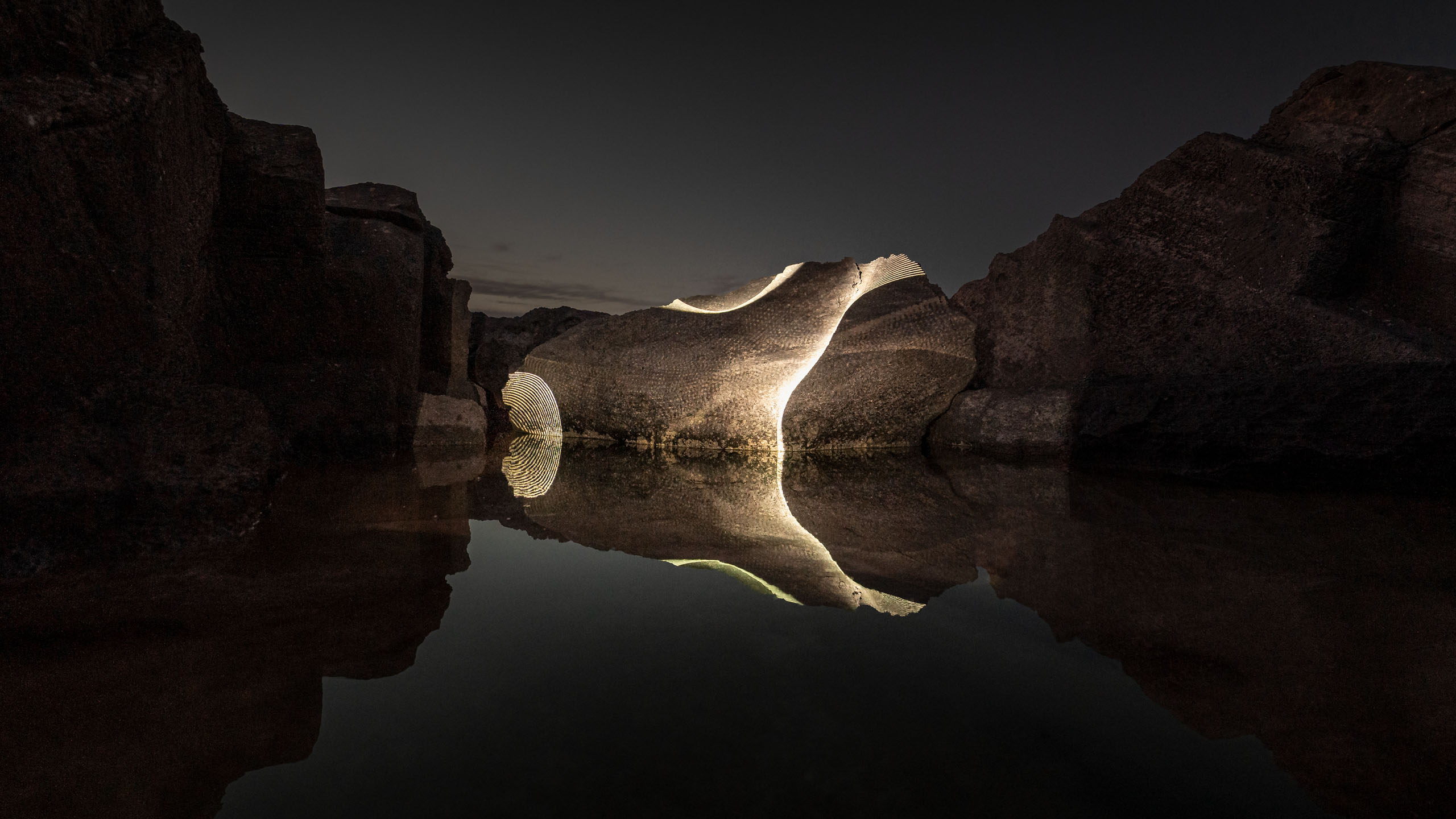 Video-mapping projections in nature on a beautiful boulder mirrored in calm water