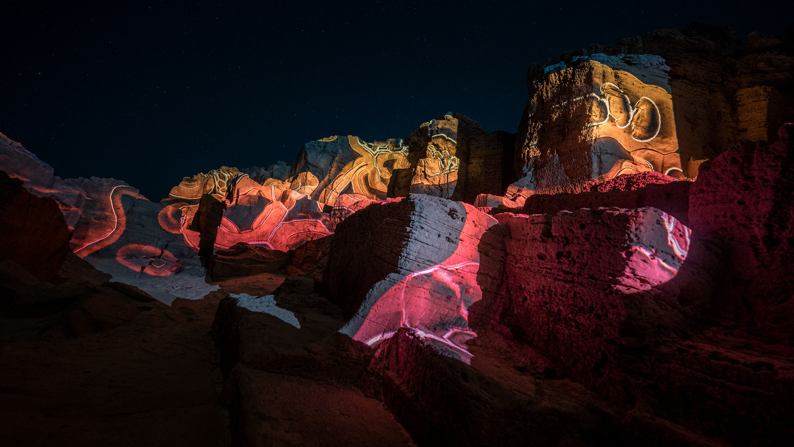 Video-mapping projections in nature on a huge rock landscape with colorful graphic pattern