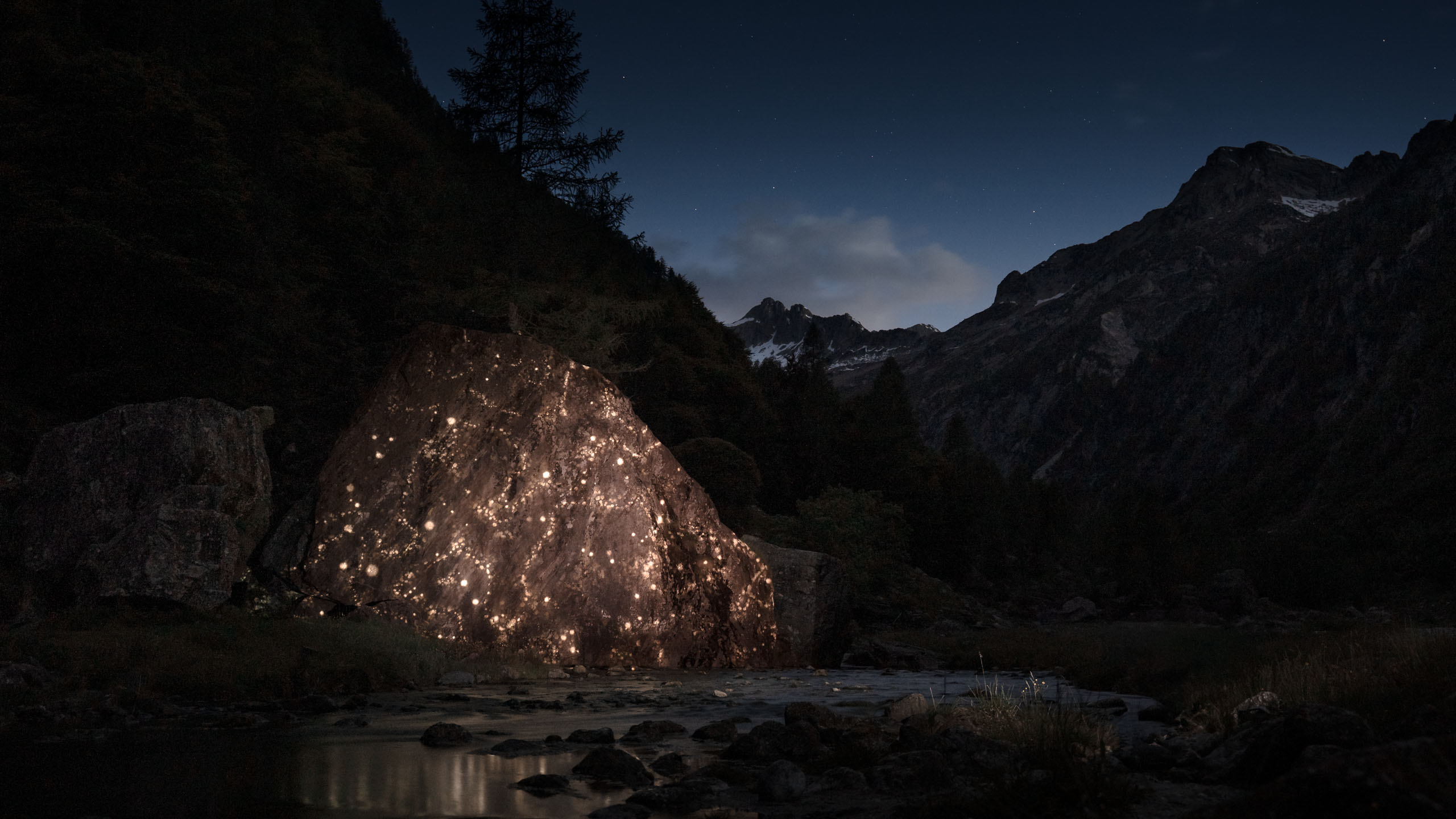 Immersive projection mapping on mountain boulder at night – glowing light points by Philipp Frank in alpine nature setting