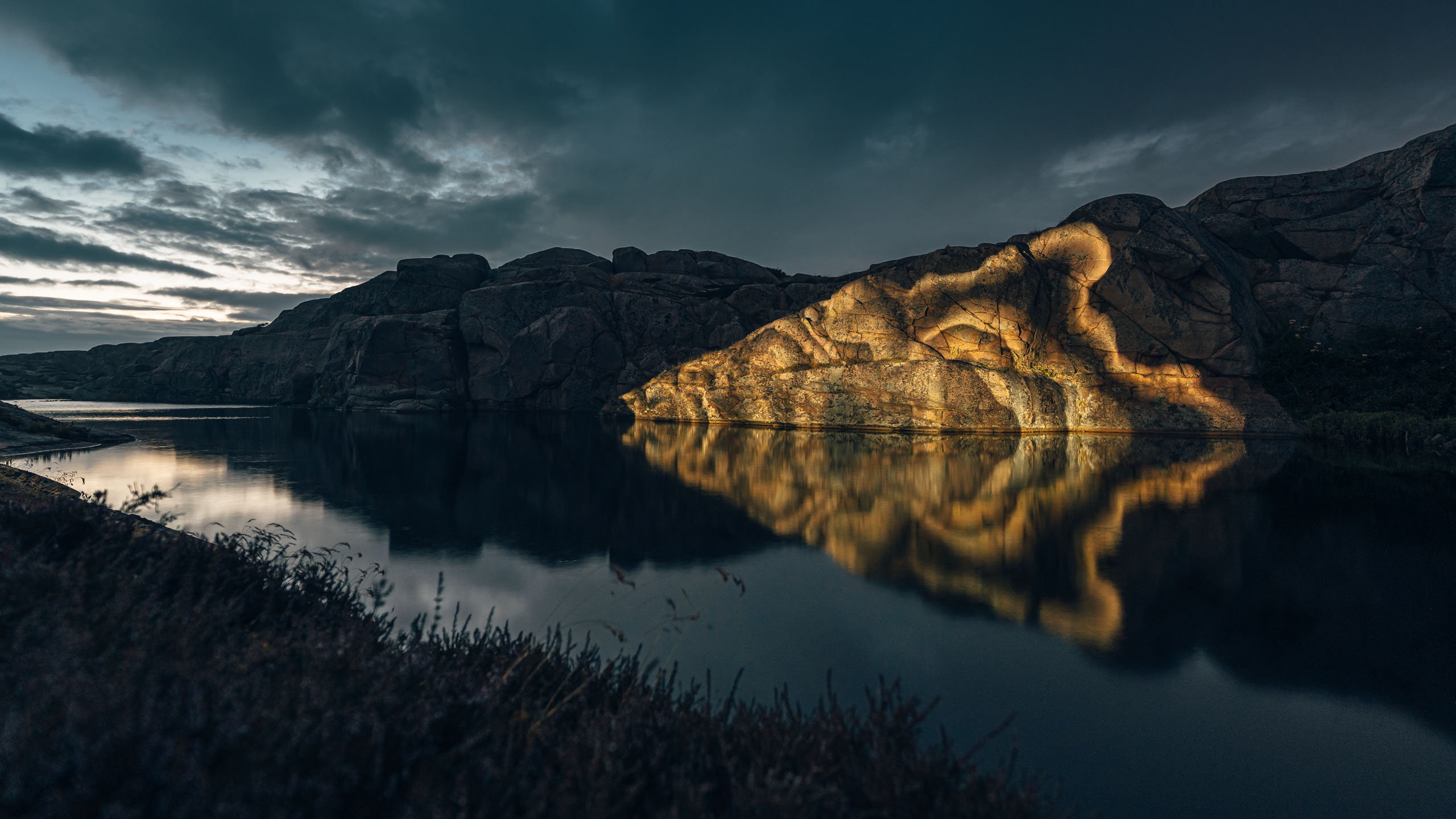 Light projection by Philipp Frank onto a coastal rock formation in Smögen – glowing contours reflected in the water reveal the hidden vibrational geometry of nature.