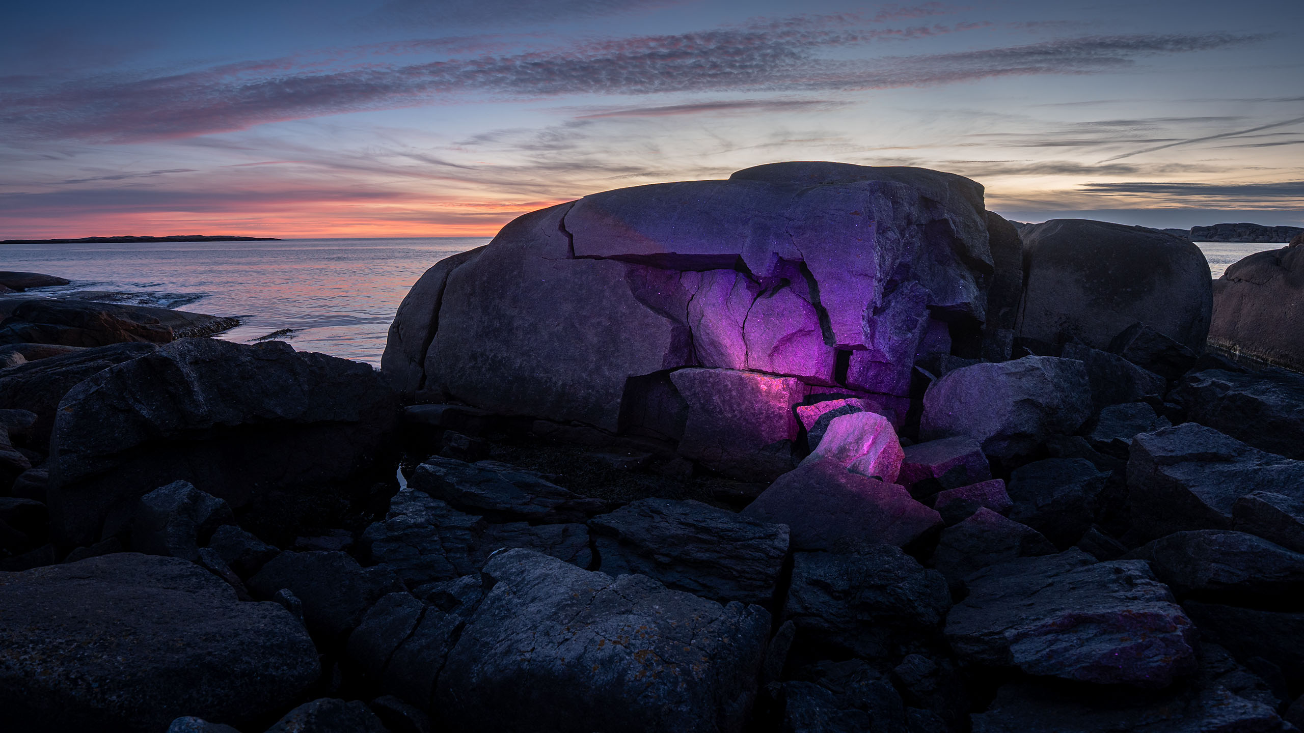 Lithogenesis by Philipp Frank – subtle purple light projection into cracks of a coastal rock formation in Smögen, Sweden. Site-specific light art installation at the edge of land and sea.
